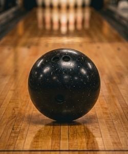 Close up of bowling ball on bowling alley wiht ten pins in background